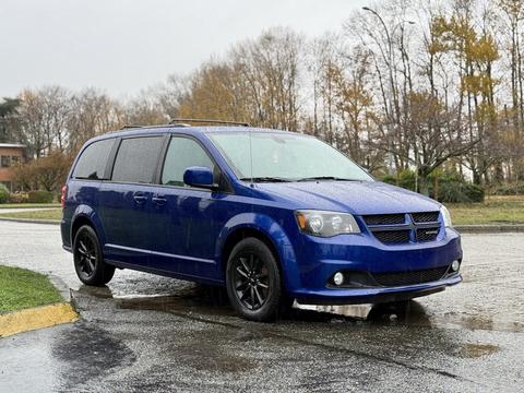 A blue 2020 Dodge Grand Caravan with black wheels parked on wet pavement