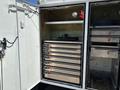 A 2017 Ford F-550 with an open storage compartment featuring multiple metallic drawers and a shelf with a circular gauge