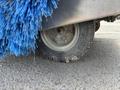 A close-up view of a blue brush attached to the side of a 2023 Bitimec SC415 with a rubber tire partially visible beneath the brush