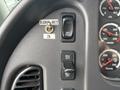Close-up of a dashboard control panel from a 2013 Freightliner 114SD featuring switches for radio output speed control and cruise settings