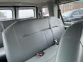 Interior view of a 2010 Ford Econoline van showing two rows of gray leather seats with seat belts
