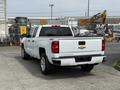 A white 2018 Chevrolet Silverado 1500 pickup truck is parked with its rear facing the viewer displaying the Chevrolet logo and the Silverado name on the tailgate