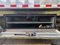 A storage compartment on the back of a 2022 Freightliner M2 106 truck with open doors revealing shelves and equipment inside