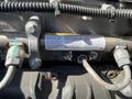 A close-up of a 2022 Freightliner Cascadia engine component featuring pipes bolts and a warning label about pressure and fuel system maintenance