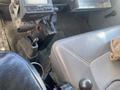 Interior of a 1997 Freightliner FL70 showing the driver’s seat and gear shift with a dashboard display and an area for storage