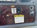Dashboard controls of a 2022 Freightliner M2 106 showing speed limit sign a warning label and a power outlet