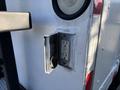 A weathered electrical outlet mounted on the side of a white vehicle with a round light above it