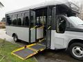 A 2020 Chevrolet Express bus with an open door and a wheelchair ramp extended down