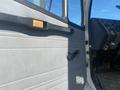 The interior of a 1997 Freightliner FL70 showing a gray door panel with a black handle and window crank