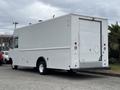 A white 2018 Ford Econoline van with a flat rear design and door system featuring dual side access panels and large wheels