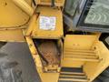 A rusty compartment of a 2012 John Deere 310SJ backhoe with exposed hydraulic lines and a manufacturer label attached to the side