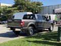 A gray 2018 Ford F-150 truck with a four-wheel drive badge parked at an angle showing its rear and side features