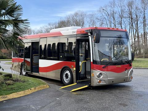 A red and silver 2016 Grande West Vicinity bus with an open door and a wheelchair ramp extended