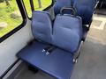 A row of two blue upholstered seats with seatbelts inside a vehicle designed for transport