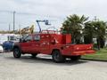 A red 2013 Ford F-550 with a flatbed and equipment storage compartments is parked, showcasing its utility design and sturdy build