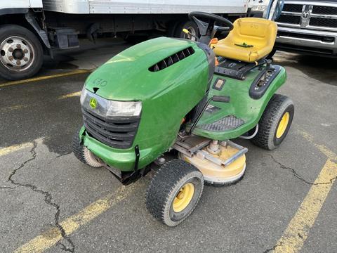 A green 2021 John Deere L Series S riding lawn mower with a yellow seat and large black engine cover resting on four wheels