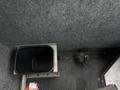 A black plastic storage bin installed in the interior of a 2012 Ford Econoline alongside a metal strap on the floor
