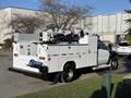 A 2009 Ford F-550 service truck with a flatbed, utility compartments and a hydraulic lift mounted on the rear