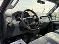 Interior view of a 2015 Ford F-550 showcasing the steering wheel dashboard and controls with gray upholstery and a spacious layout