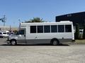 A 2020 Chevrolet Express bus in white with large windows parked on a street