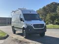 A 2024 Mercedes-Benz Sprinter 2500 van with a sleek design featuring a silver body and roof racks visible on top