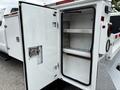 A 2013 Ford F-250 SD with a white service body featuring an open storage compartment and shelving inside