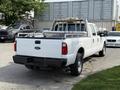 A white 2011 Ford F-350 Super Duty with a utility bed and rack is parked with its back facing the viewer
