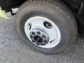 Close-up of a tire and wheel assembly from a 1976 GMC Palm Beach featuring a white rim with a chrome center hub displaying the GMC logo and a textured black tire