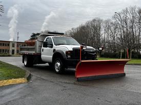 A 2009 Ford F-550 truck equipped with a large red snowplow attached to the front