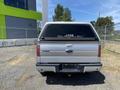 A rear view of a silver 2014 Ford F-150 with a Leer cap on the truck bed and a Ford emblem on the tailgate