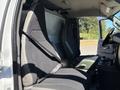 The interior of a 2019 GMC Savana featuring two front bucket seats with seatbelts and a central console with cup holders