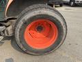 A close-up of a large agricultural tire from a 2010 Kubota M6040 featuring a prominent orange rim and a rugged black tread pattern