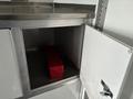 An open storage compartment of a 2020 Freightliner MT45 revealing a red toolbox inside
