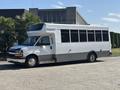 A 2020 Chevrolet Express shuttle bus with a white exterior and large windows parked on a street