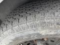 A close-up of a tire with a heavily worn tread pattern and the word Rhodes clearly visible on the sidewall