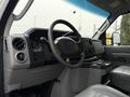 Interior view of a 2019 Ford Econoline showing the dashboard steering wheel and gear shift with controls and cup holders visible