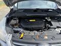A 2015 Ford Escape with the hood open revealing the engine compartment and various components including a battery coolant reservoir and engine cover