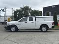 A white 2016 RAM 1500 pickup truck with a canopy over the bed parked on a concrete surface