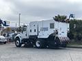 A 2012 International DuraStar 4300 street sweeper with a white body and rear-mounted broom attachment