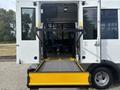 A 2020 Chevrolet Express with an open ramp for accessibility leading into the passenger area featuring blue seats and a flat floor
