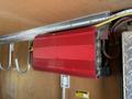 A red power inverter installed inside a vehicle with ventilation grills and connected wiring