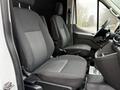 Interior view of a 2020 Ford Transit showing two front seats in black fabric with a patterned design and a dashboard area with controls and a gear shift