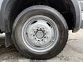 A close-up of a silver wheel and tire from a 2007 Ford F-550 showing the tread pattern and the wheel's design with lug nut holes
