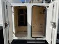 A white 2010 Freightliner M2 106 truck with open side compartments revealing metal hooks and shelves inside