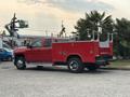 A red 2015 Chevrolet Silverado 3500HD truck with a service body and dual rear wheels parked with visible tool compartments on the side