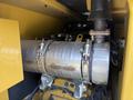 Close-up of the exhaust system on a 2022 Caterpillar 306 featuring a metallic cylindrical component with clamps and several connecting pipes