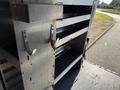 A metal shelving unit with multiple drawers and hooks designed for storage in a 2023 Mercedes-Benz Sprinter 2500 van