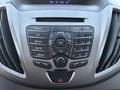 Dashboard control panel of a 2016 Ford Transit 150 featuring a radio display and multiple buttons for media navigation and settings