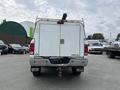 A white 2015 RAM 2500 truck with a utility bed and a ladder rack mounted on top viewed from the rear
