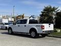 A white 2018 Ford F-150 pickup truck parked with a crew cab and 4x4 designation visible on the side